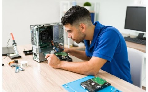 Joven técnico en mantenimiento de computadores arreglando computador de mesa